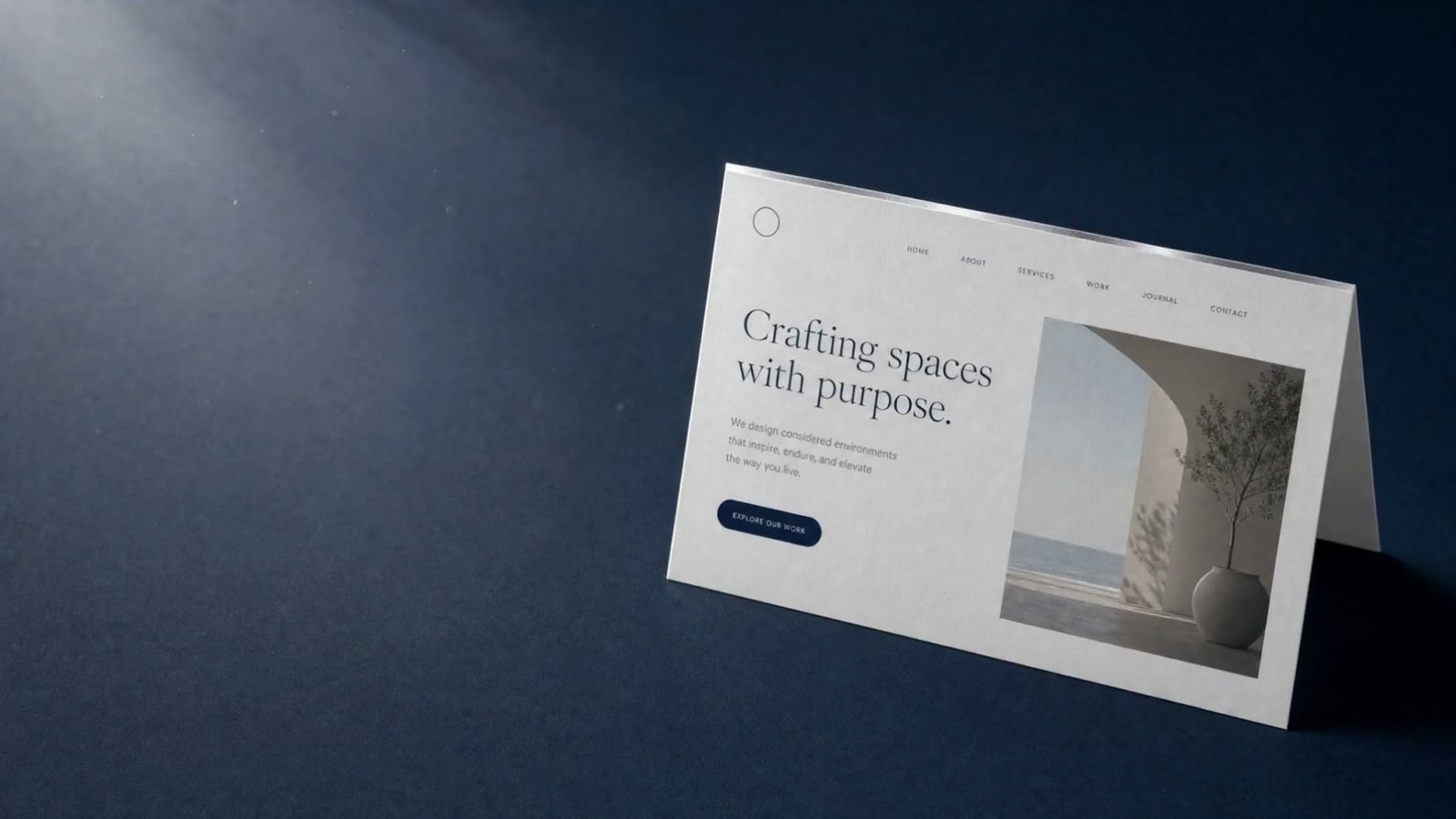 A crisp folded card printed with a clean modern homepage, standing on a navy desk